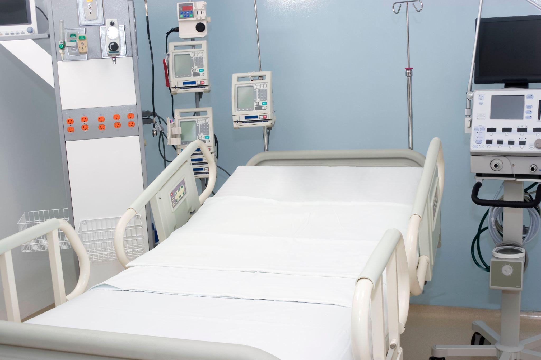 A Hospital Bed With Medical Machines Around It And The Room Is Painted Blue