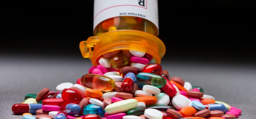 A prescription pill bottle spilling out an assortment of pills.