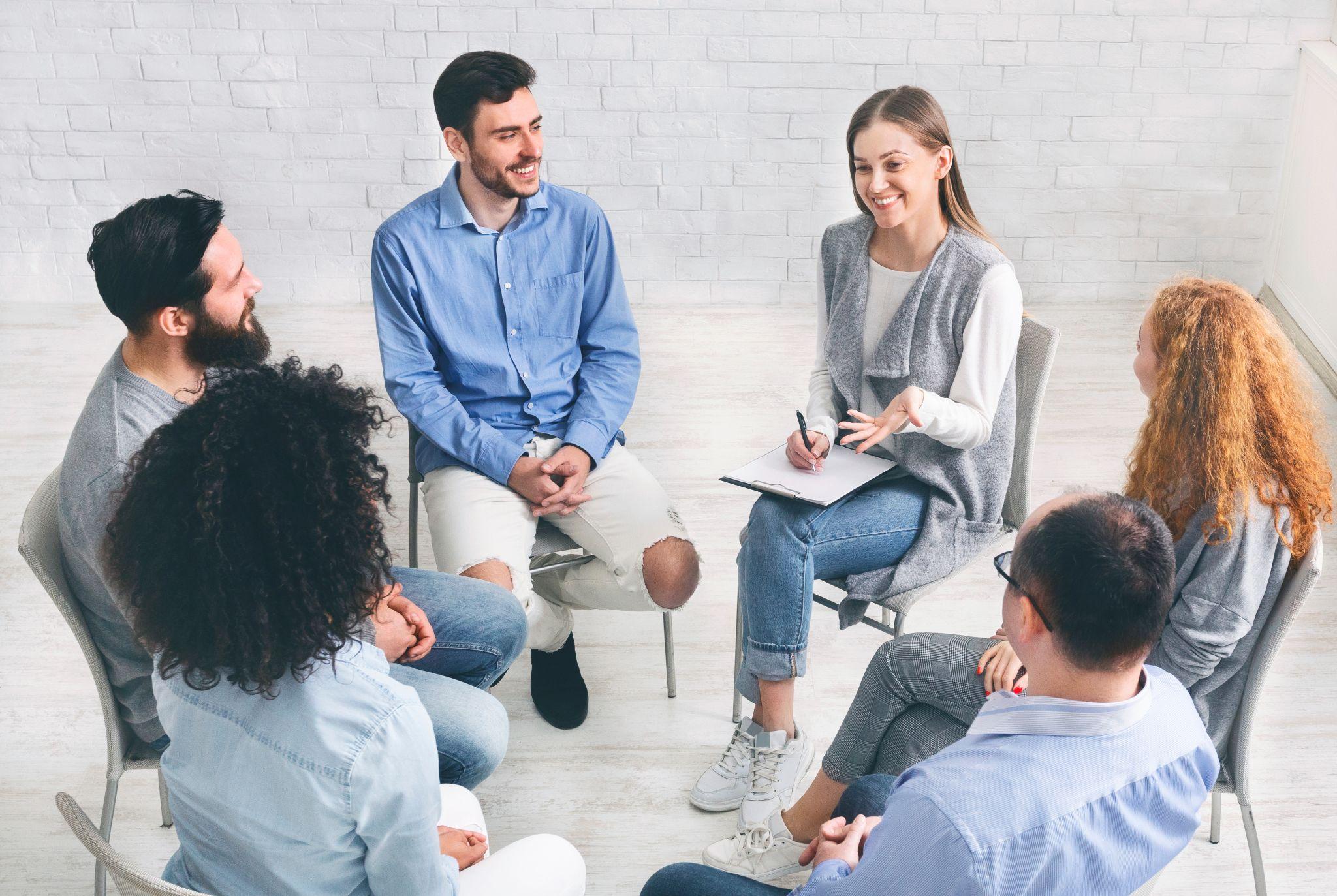Diverse happy people sitting in trust circle on therapy session