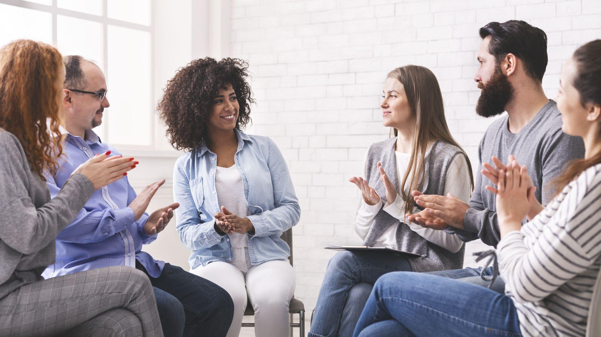 Group of diverse people applauding to themselves at therapy session in rehab