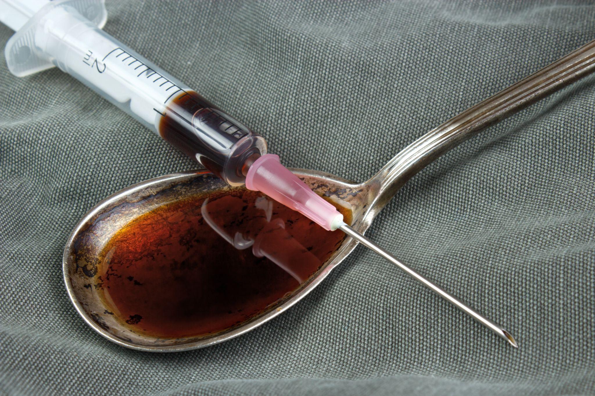 Drug syringe and cooked heroin on spoon
