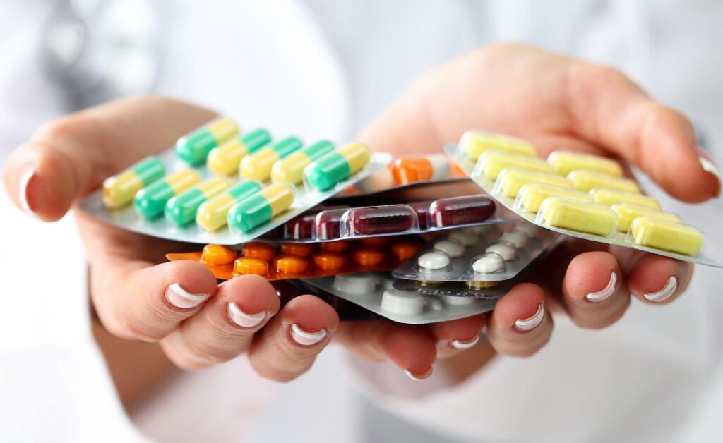 female doctor hand holding pack of different tablet blisters