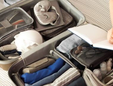Female hands packing traveler case on bed