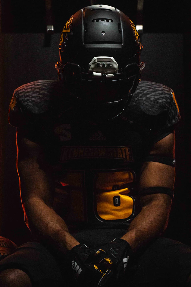 Football Player With Black Helmet Sitting On Dark