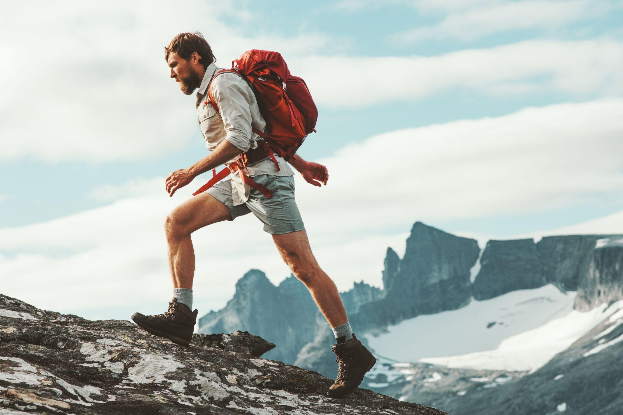 man trail running in mountains with backpack