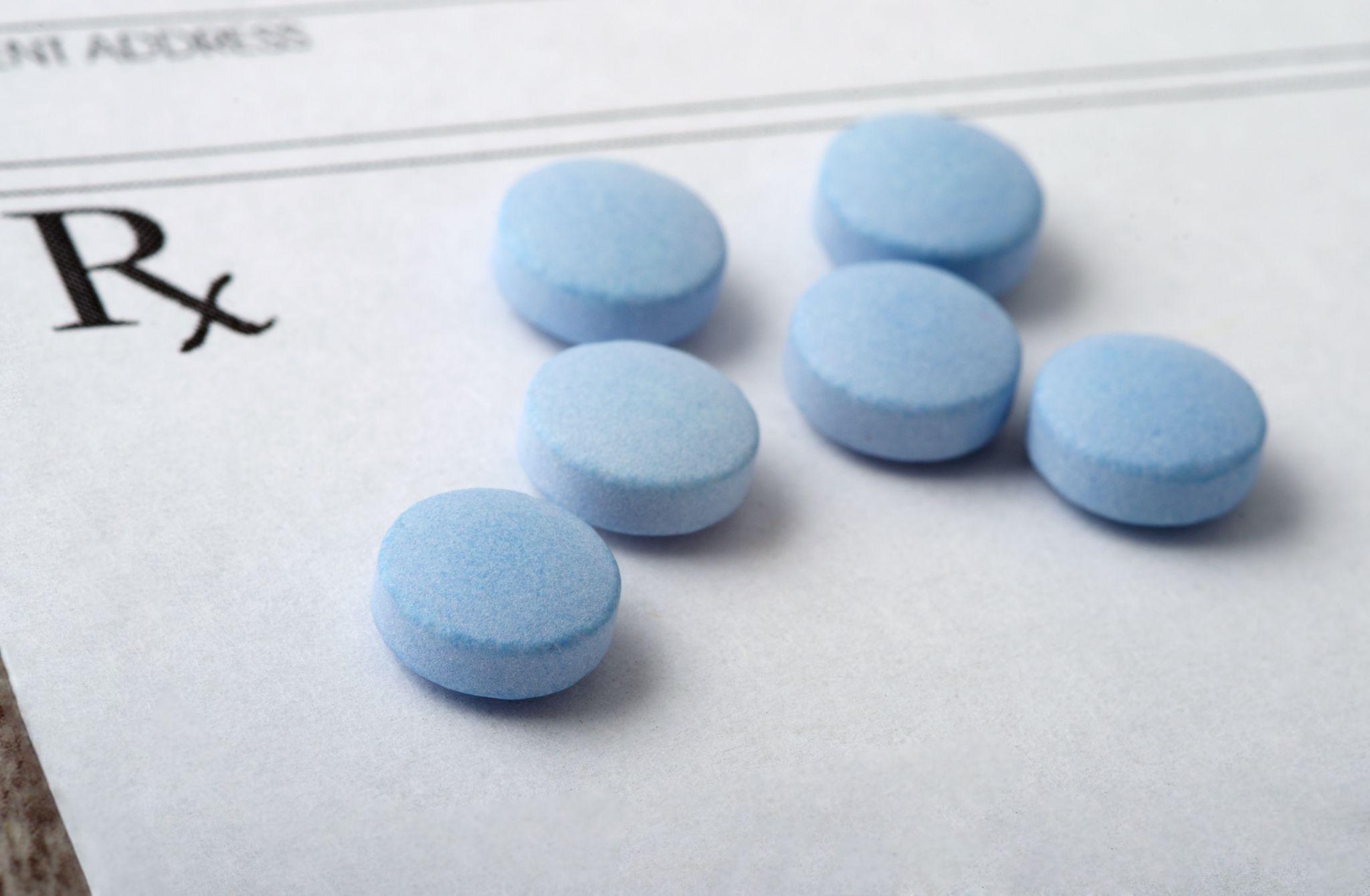 round blue pills spread out on a blank prescription form