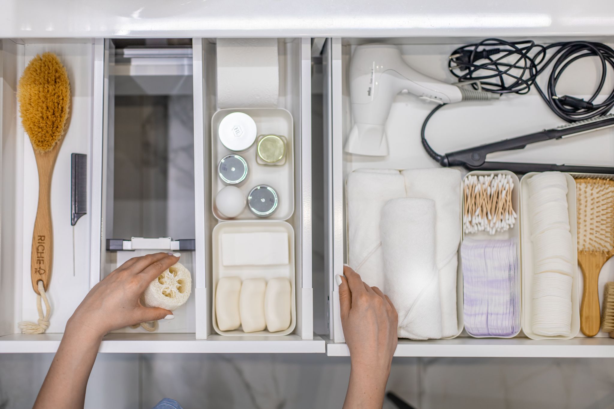  woman hands organizing bathroom amenities and toiletries in drawer